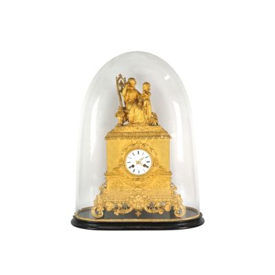 une horloge dorée sous un dôme en verre, sur fond blanc