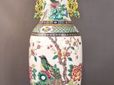 un grand vase orné d'un oiseau, posé sur une table