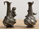 two silver vases sitting on top of a wooden table