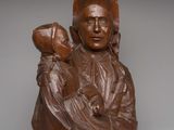 statue of a woman holding a child on a wooden base