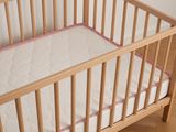 a baby crib with a mattress and a pillow in it