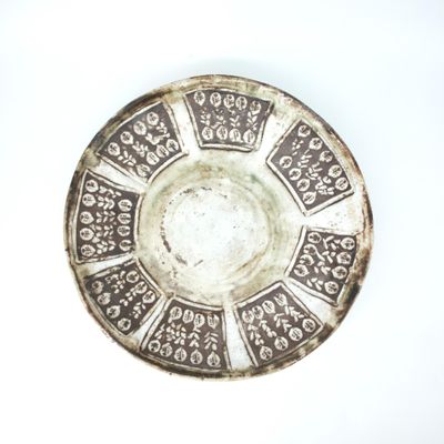 une assiette en argent posée sur un fond blanc et ornée d'un motif