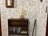 a book shelf with books and a clock in the corner of a room