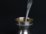 a silver cup with a spoon in it on a black background