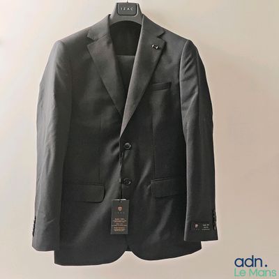grey suit jacket hanging on a hanger on a white wall