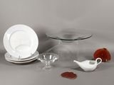 une table en verre sur laquelle sont posés une assiette, un bol, une soucoupe et une soucoupe