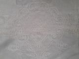 embroidered table cloth with a white design on it