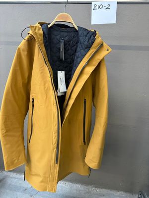 une veste jaune suspendue à un cintre devant un mur gris
