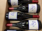 six bouteilles de vin rouge dans un carton sur une table