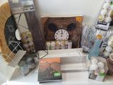 many items on a table that include a clock, a fan, a fan, a book, and other items