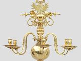 un lustre ancien en laiton, muni de trois bougies et surmonté d'un oiseau