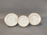 three white and gold china plates with gold rims