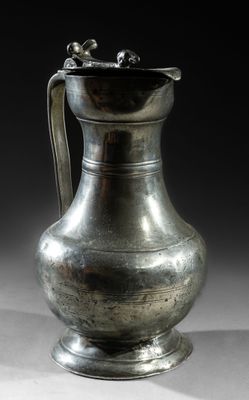 a silver vase sitting on a table with a black background