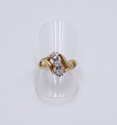 un gros plan d'une bague en or et diamants posée sur un présentoir transparent