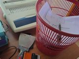 un panier rouge posé sur une table, à côté d'une machine à écrire et d'autres fournitures de bureau