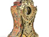 a gold and red clock sitting on top of a stand
