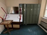 a room with a desk, lockers, and a mirror in it