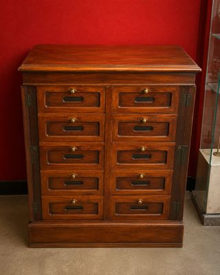 une commode en bois dans une pièce aux murs rouges
