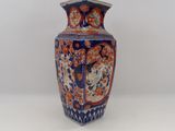 un vase bleu et orange posé sur une surface blanche