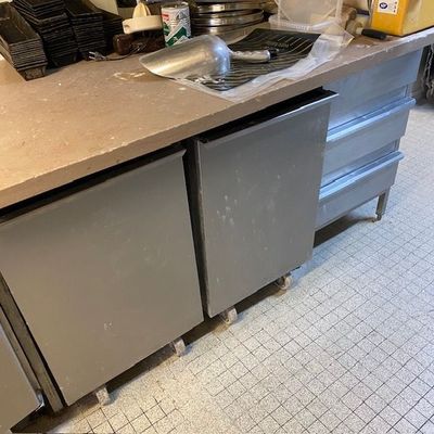 une photo d'une cuisine équipée d'appareils électroménagers et de plans de travail en acier inoxydable