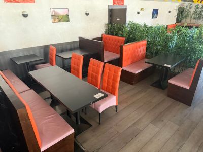 tables and chairs in a restaurant with orange seats and wood flooring
