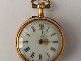 a gold pocket watch with roman numerals on the face