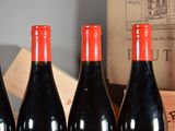 three bottles of red wine are lined up on a table