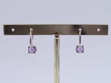 pair of earrings with amethorate stones on a metal stand