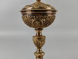 une coupe en or richement décorée, surmontée d'une croix