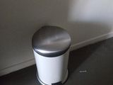 a trash can sitting in the corner of a bathroom