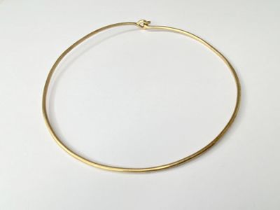 a close up of a gold necklace on a white surface