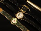 two watches and a pen on a black surface