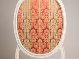 une image représentant une chaise dont l'assise est recouverte d'un tissu rouge et or