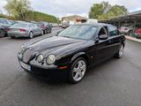 La Jaguar noire est garée sur un parking, à côté d'autres voitures.