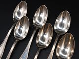 six silver spoons are lined up in a row on a black surface