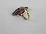 a close up of a gold ring with a red stone