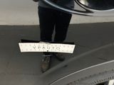 a person standing in front of a car holding a sign