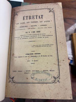quelqu'un tient un livre ouvert sur une table où se trouvent plusieurs autres livres