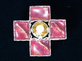 a pink cross with a yellow center on a black background