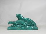 a green statue of two lions laying down on a white surface
