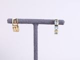 pair of gold and aquamarinee earrings on a display stand