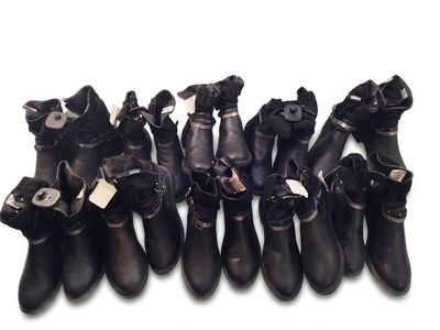 Plusieurs paires de bottes en cuir noir sont alignées sur une surface blanche