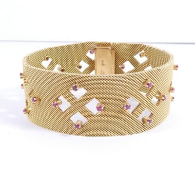 a close up of a gold bracelet with pink stones