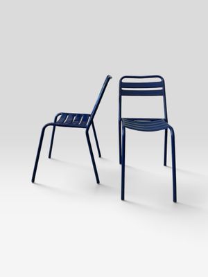 two blue chairs sitting next to each other on a white surface