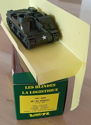 un petit char de jouet posé sur une boîte, elle-même posée sur une table