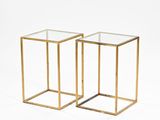 a pair of gold metal and glass side tables