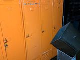 orange lockers in a room with a trash can and a trash can