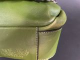 the green purse has a silver clasp on the handle