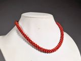 a close up of a red beaded necklace on a mannequin