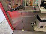 un évier dans un coin de la cuisine, avec une poubelle
